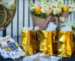 Golden gift bags with flowers and Senior Night programs on display at an event table.