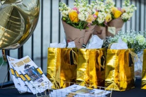 Golden gift bags with flowers and Senior Night programs on display at an event table.