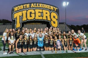 North Allegheny Tigers field hockey team group photo on the field under stadium lights.
