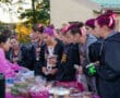 Group of girls with pink ribbons buying treats at an outdoor bake sale.