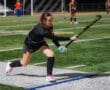 Field hockey player prepares to strike the ball on a green sports field during a game.