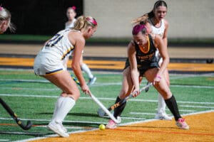 Field hockey players competing during a match on grass, focusing on ball control and teamwork.