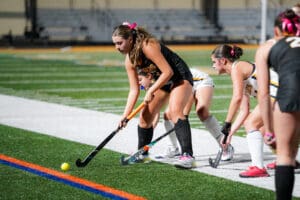 Field hockey players in action, focused on approaching ball during a night match.