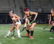 Girls playing field hockey under stadium lights, focused on the ball.