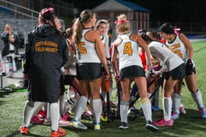 North Allegheny field hockey team huddles on the field, preparing for the game at night.