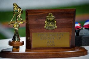 Field hockey runner-up trophy for AAA 2025 displayed on a table with a golden player figurine.