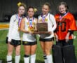 Girls' field hockey team with medals, holding a runner-up plaque on a sports field.