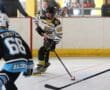 Youth inline hockey player in action, maneuvering puck on rink during a competitive game.