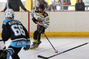 Youth inline hockey player in action, maneuvering puck on rink during a competitive game.