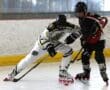 Two hockey players in action on an indoor rink, competing for the puck.