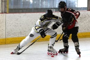 Two hockey players in action on an indoor rink, competing for the puck.
