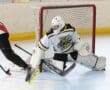 Roller hockey goalie makes a save against an attacking player in a match.