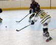 Inline hockey player taking a shot on goal while the goalie prepares to block. Action-packed game moment.