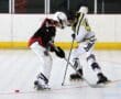 Two inline hockey players in action on the rink, competing for the puck during a game.