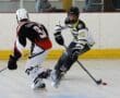 Two inline hockey players competing on the rink, one in white and yellow, the other in black and red jerseys.