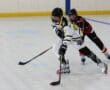 Two players compete in a thrilling roller hockey match on an indoor rink, showcasing speed and skill.