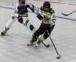 Youth roller hockey players compete on rink during a game, wearing colorful jerseys and helmets, with sticks and puck.