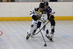 Two hockey players in action on a rink, competing for the puck during an intense game.