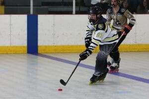 Roller hockey player in white and black jersey, number 91, in action with puck. Indoor rink match scene.