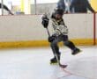 Roller hockey player in action, taking a dynamic shot on goal inside an indoor rink.