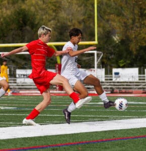 Two soccer players in action on the field, vying for the ball with intensity during a match.