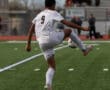Soccer player in white jersey, number 9, mid-action on a field with blurred spectators in the background.