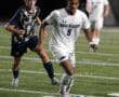 Soccer player dribbling the ball during a match between North Allegheny and Butler, wearing a white jersey with number 9.
