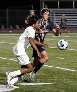 Two soccer players in action on the field, vying for the ball during a night match.