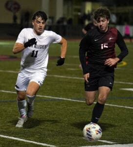 Two soccer players competing for the ball during a night game on a grass field.
