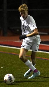 Soccer player dribbling the ball with focus during a night match on the field.