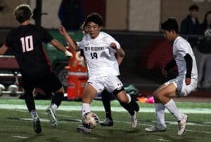 Soccer players in action during a night match, focused on dribbling and teamwork on the field.