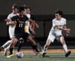 High school soccer match action shot, players competing for the ball under stadium lights.