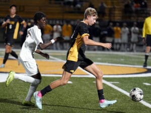 Soccer players in action during a night match on a field with spectators in the background.