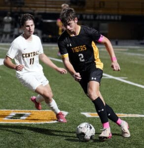 Soccer players in action during a match, focusing on ball control and agility on a green field.