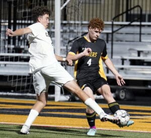 Two soccer players compete for the ball on the field during a night match.