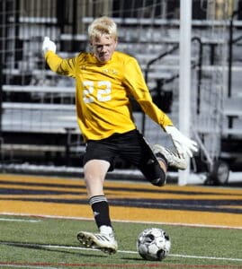 Goalkeeper in yellow jersey kicking soccer ball on field during a game.