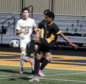 Soccer players in black and white uniforms compete for the ball on a field during a match.