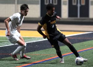 Soccer players competing intensely on the field during a night game.