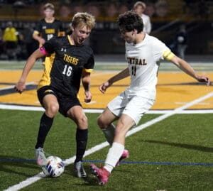 Two soccer players in action on the field during a competitive night match.