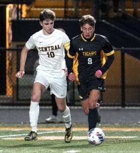 Two soccer players in action during a competitive night match, both focused on controlling the ball on the field.