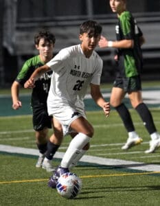 Soccer player dribbling past opponent on field during a night match.