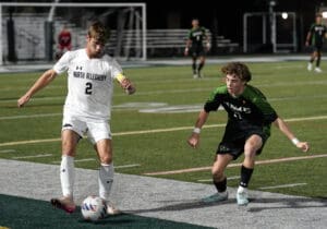 Two soccer players in action during a nighttime match, focused on the ball near the sideline.