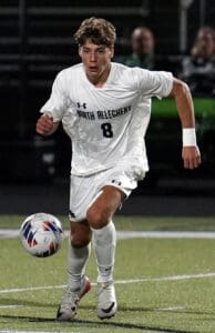 Young soccer player in action on the field, running towards the ball.