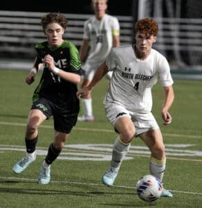 High school soccer players in action during a night match.