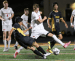 Soccer players from opposing teams compete for the ball during a high-energy night match on the field.