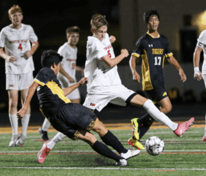 Soccer players from opposing teams compete for the ball during a high-energy night match on the field.
