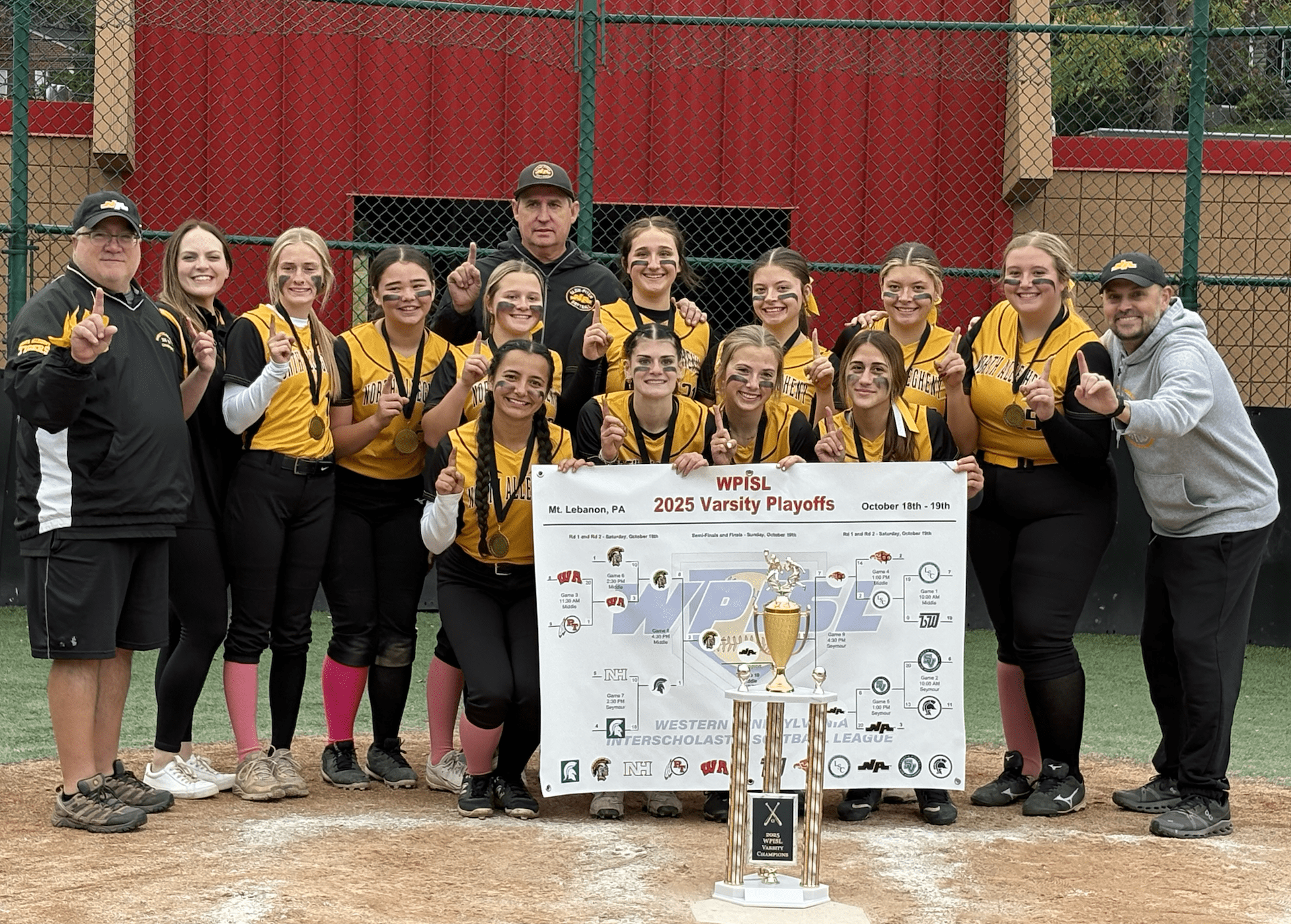 Softball team celebrates winning the 2025 WPISL Varsity Playoffs, holding trophy and banner on field.