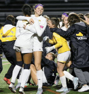 Soccer team celebrating victory on the field with joyful hugs and smiles.