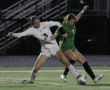 Girls' soccer match action, players competing for ball on field at night.