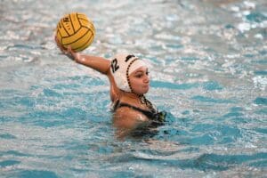 Water polo player in action, poised to throw the ball in a pool.